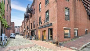 A cobblestone street lined with brick buildings, one with a sign reading "Central Provisions." - Superb Location! Heart of Old Port-Spacious Apartment (Portland)