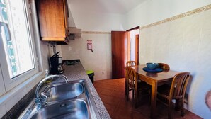A kitchen with a sink, stove, and a dining table with chairs. - Quinta dos Moledros (Figueira)
