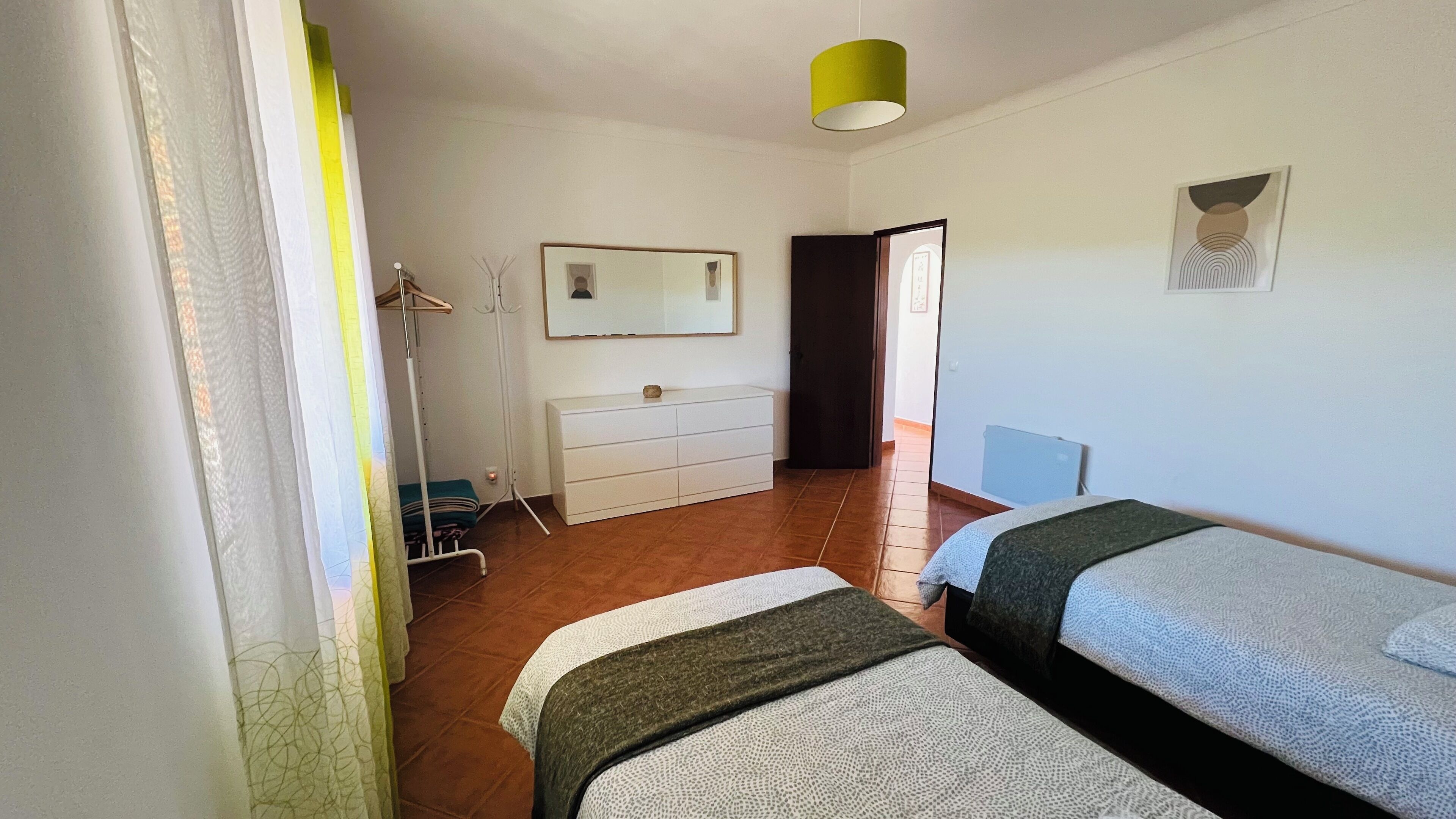 Un dormitorio con dos camas, un aparador, un espejo y una puerta que da a otra habitación.