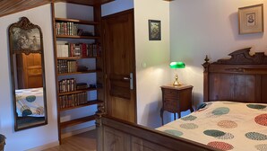 A bedroom with a wooden bed, a green desk lamp, a bookshelf, and a framed picture on the wall. - Quiet country house animals welcome minimum nights 13! (Léotoing)