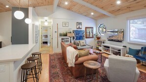 A spacious living room with a high ceiling, a cozy seating area, and a television. - Pino Point Steps to Tahoe Beaches (Kings Beach)