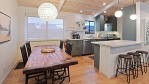 A modern kitchen with wooden flooring, a central island, and pendant lighting. - Pino Point Steps to Tahoe Beaches (Kings Beach)
