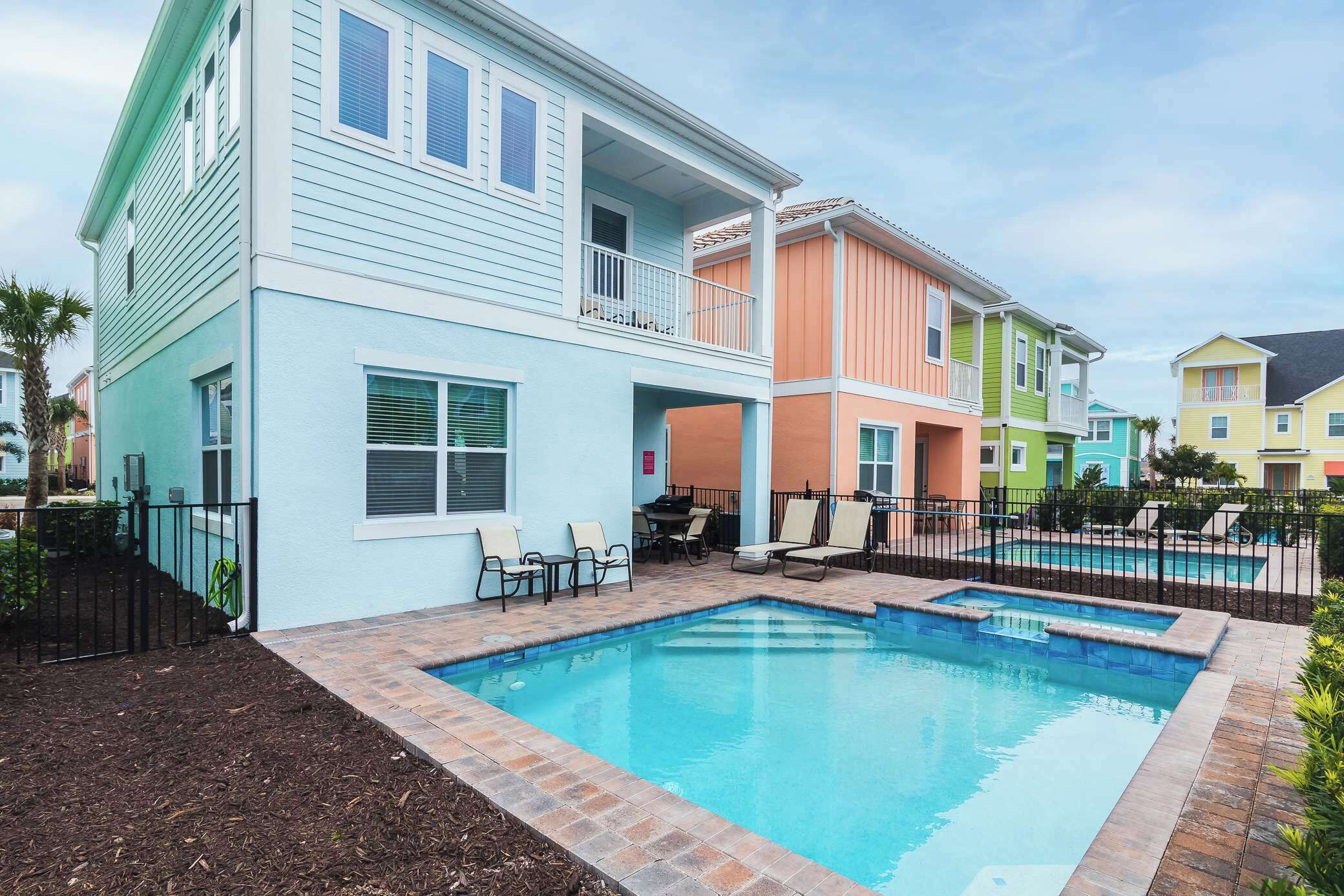 Edificio residencial con piscina, mobiliario exterior y patio cercado.