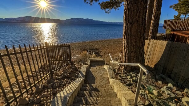 A coastal pathway leading to a beach with a metal fence, stone steps, and a tree. - Singing Pines in Marla Bay - Walk to Lake! (Zephyr Cove)