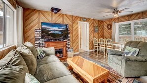 A cozy living room with a fireplace, comfortable seating, and a large TV. - Whispering Pines Cabin - Family and pet Friendly Abode (South Lake Tahoe)