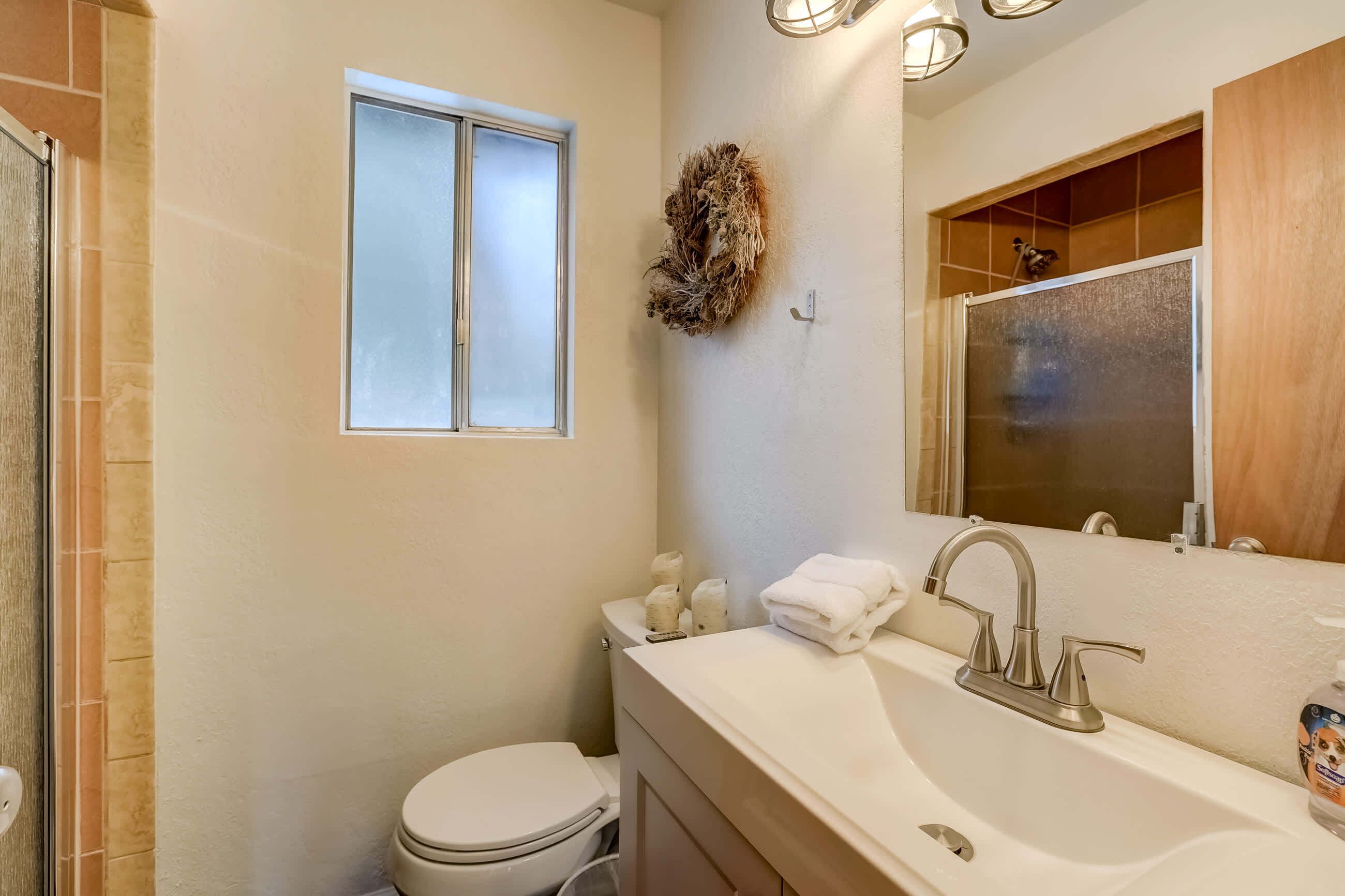 A bathroom with a toilet, sink, and window.