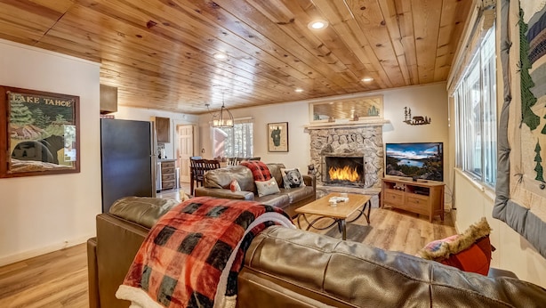Una sala de estar acogedora con chimenea, sofás de cuero, televisor y un revestimiento de piedra alrededor de la chimenea.