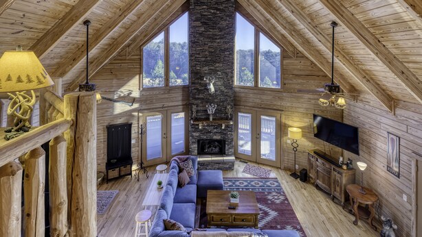Un acogedor apartamento estilo loft con chimenea de piedra, vigas de madera, ventanas amplias, un sofá, un televisor y un comedor.