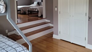 A bedroom with a bed, a staircase, and a door.