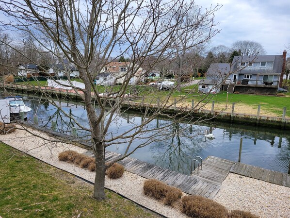 A calm river with a swan, surrounded by residential houses and a dock.