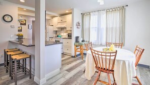 A modern kitchen with white cabinets, a central island, and a dining area with a round table and wooden chairs. - Peaceful Hurley Retreat ~ 1 Mi to Main Street (Hurley)