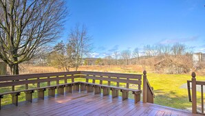 A wooden deck with benches, overlooking a grassy area with trees and a distant building. - Peaceful Hurley Retreat ~ 1 Mi to Main Street (Hurley)