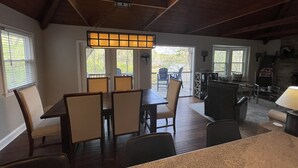 A dining area with a table and chairs, a wooden ceiling, and a view through a glass door. - The Cozy Cottage on Little Duck Cove (Roxboro)