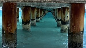 A pier extending into the water with visible rust on the supports.