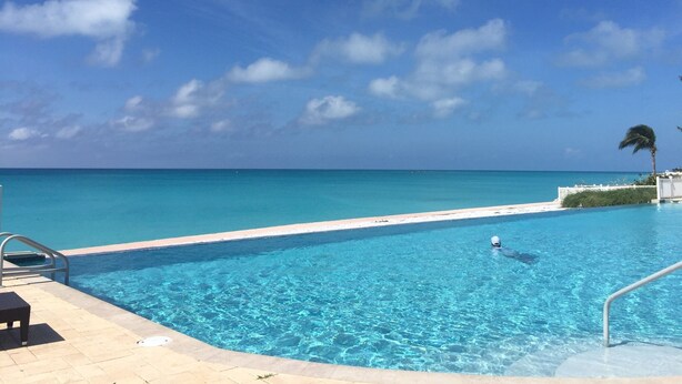 A clear blue sky, a swimming pool, and a view of the ocean.