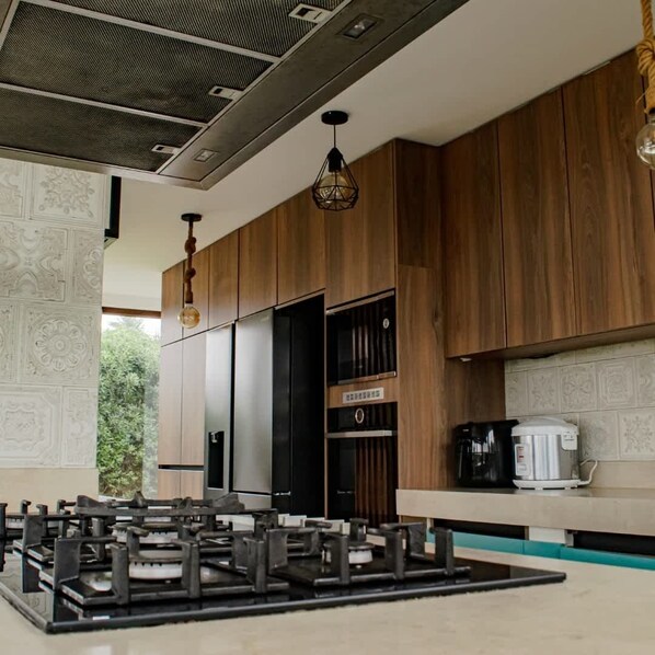 A modern kitchen with wooden cabinets, a gas stove, and a coffee maker.
