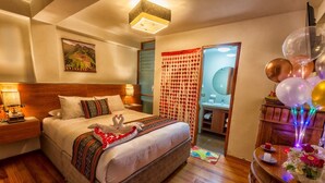 A hotel room with a large bed, wooden headboard, bedside lamps, a nightstand, a wooden dresser, and a mirror. - Chakana Inn (Machu Picchu)
