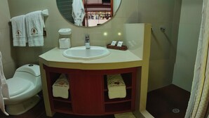 A bathroom with a white sink, a mirror, a toilet, and a shower area. - Chakana Inn (Machu Picchu)