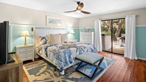 Ein Schlafzimmer mit Bett, Nachttischen, Deckenventilator und Blick ins Freie.