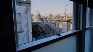 Vista desde una ventana que da a un paisaje urbano con varios edificios, incluyendo una estructura con cúpula destacada.