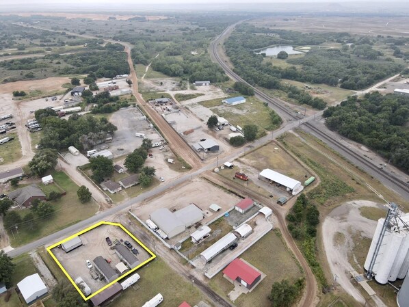 An aerial view of a rural industrial area with multiple buildings, roads, and railway tracks.