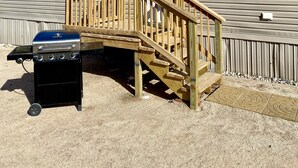 A mobile home with a wooden deck and a barbecue grill in front. - Just Dune It - East Home (Waynoka)