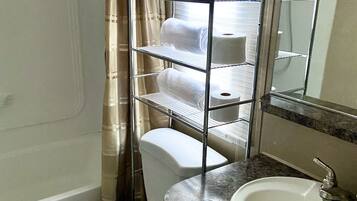Une salle de bain comprenant des toilettes, un lavabo, un porte-serviettes et un espace douche.