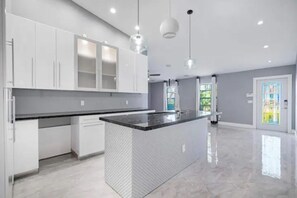 Kitchen features a central island, sleek countertop, and pendant lighting.