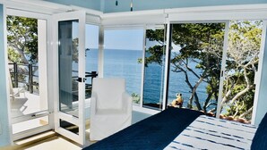 A room with a large sliding glass door leading to a balcony with a view of the sea and trees. - Exclusive Beach Front Luxe Boutique Retreat (Bahia de Banderas)