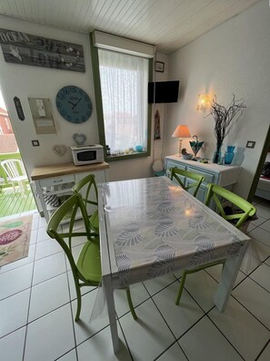 Un comedor con una mesa, sillas, un reloj, una ventana con cortinas, una lámpara y un adorno de pared.