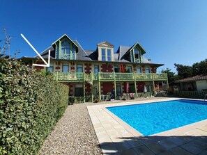 Una casa grande con piscina, un patio cubierto y un jardín bien cuidado.