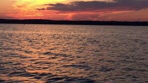Ein Sonnenuntergang über dem Wasser, im Hintergrund eine Silhouette von Land.