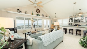 A spacious living room with a large sofa, a dining area, and a kitchen with bar stools. - Waterfront...Breathtaking View...Great Fishing...Beautiful Home!!! (Freeport)