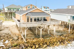 Uma casa à beira-mar com um deck de madeira e área externa coberta.