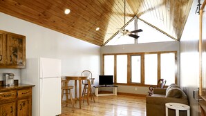 A spacious living area with wooden floors, a dining table, a sofa, and a television.