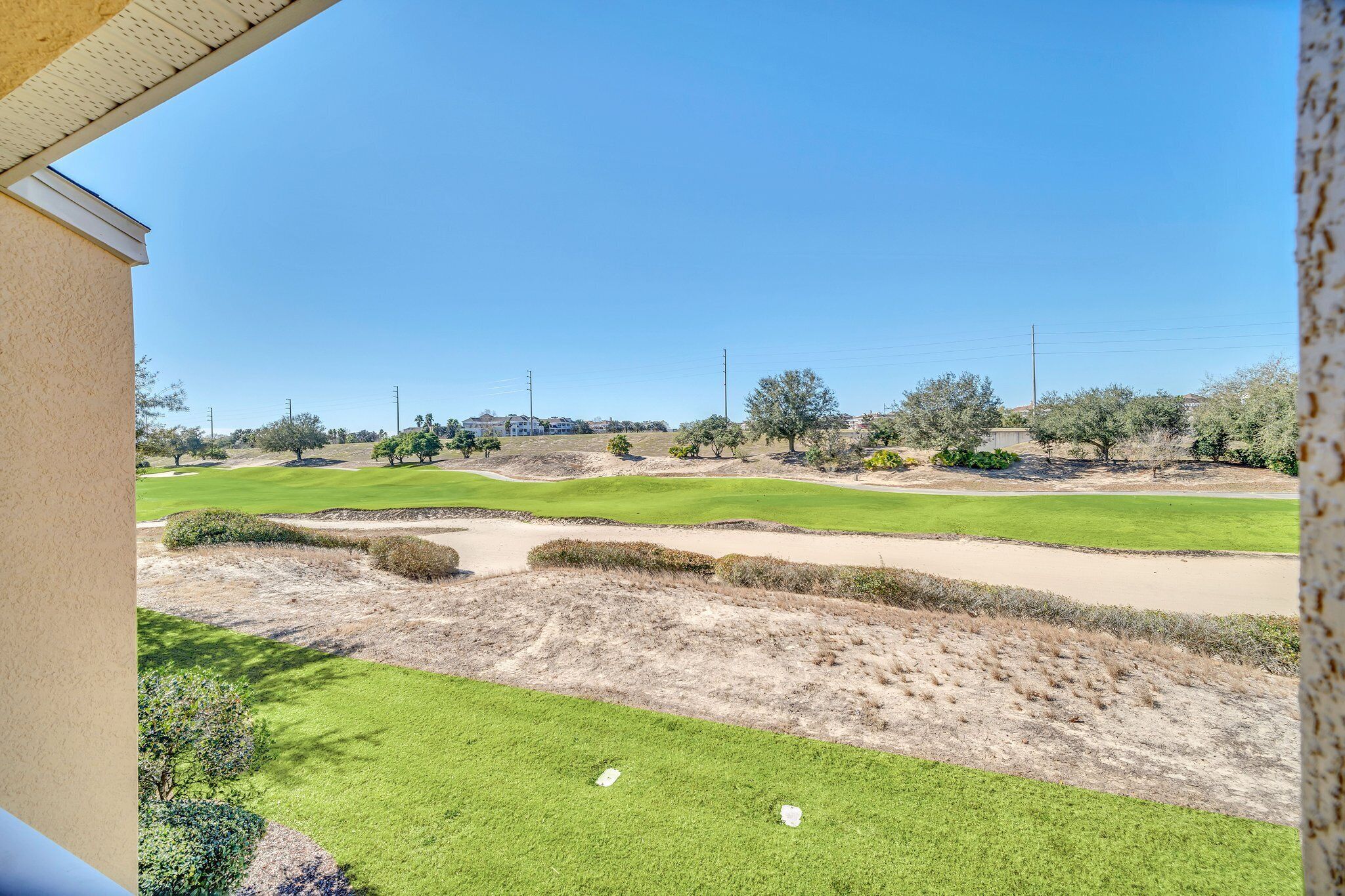A view of a golf course with sand bunkers, green areas, and trees.