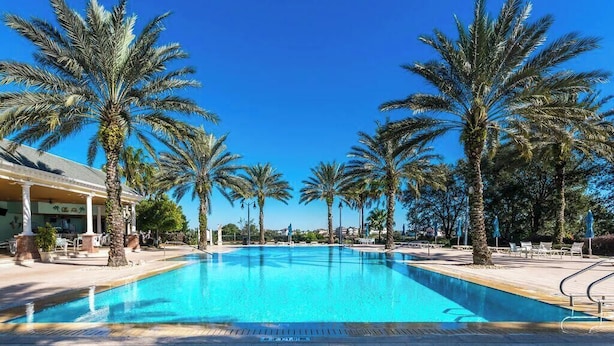Ein von Palmen umgebener Pool, mit einem Gebäude an der Seite.