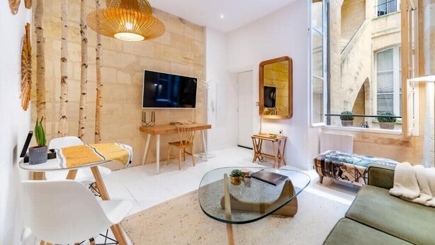 Ein modernes Wohnzimmer mit Fernseher, Glastisch und Sofa.