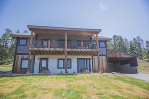 A two-story modern house with a balcony, large windows, and a garage. - New house with great views and awesome accommodations (Sturgis)