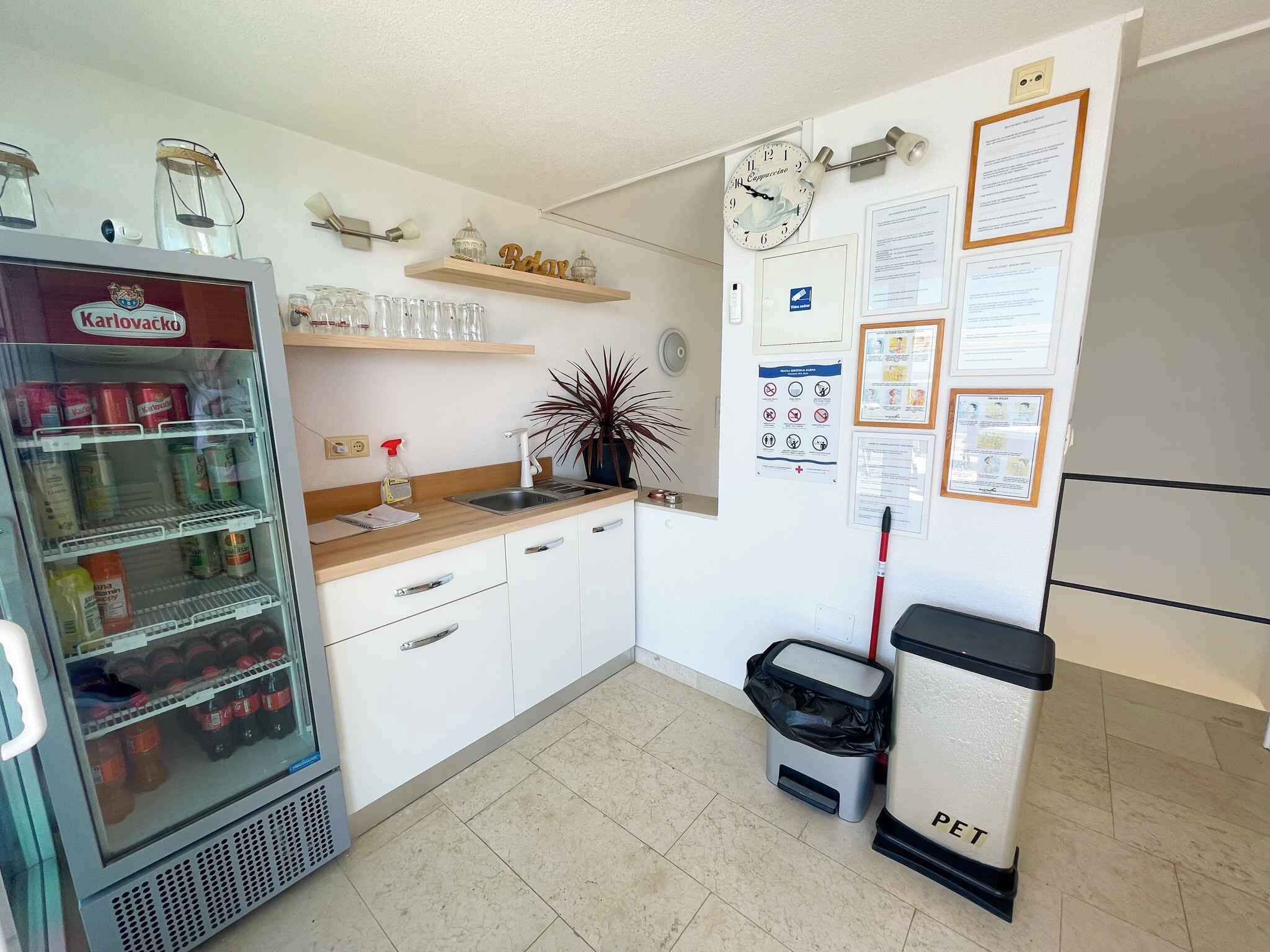 Une petite cuisine équipée d’un réfrigérateur, d’un évier et d’une poubelle portant l’inscription « DÉCHETS ANIMAUX ».
