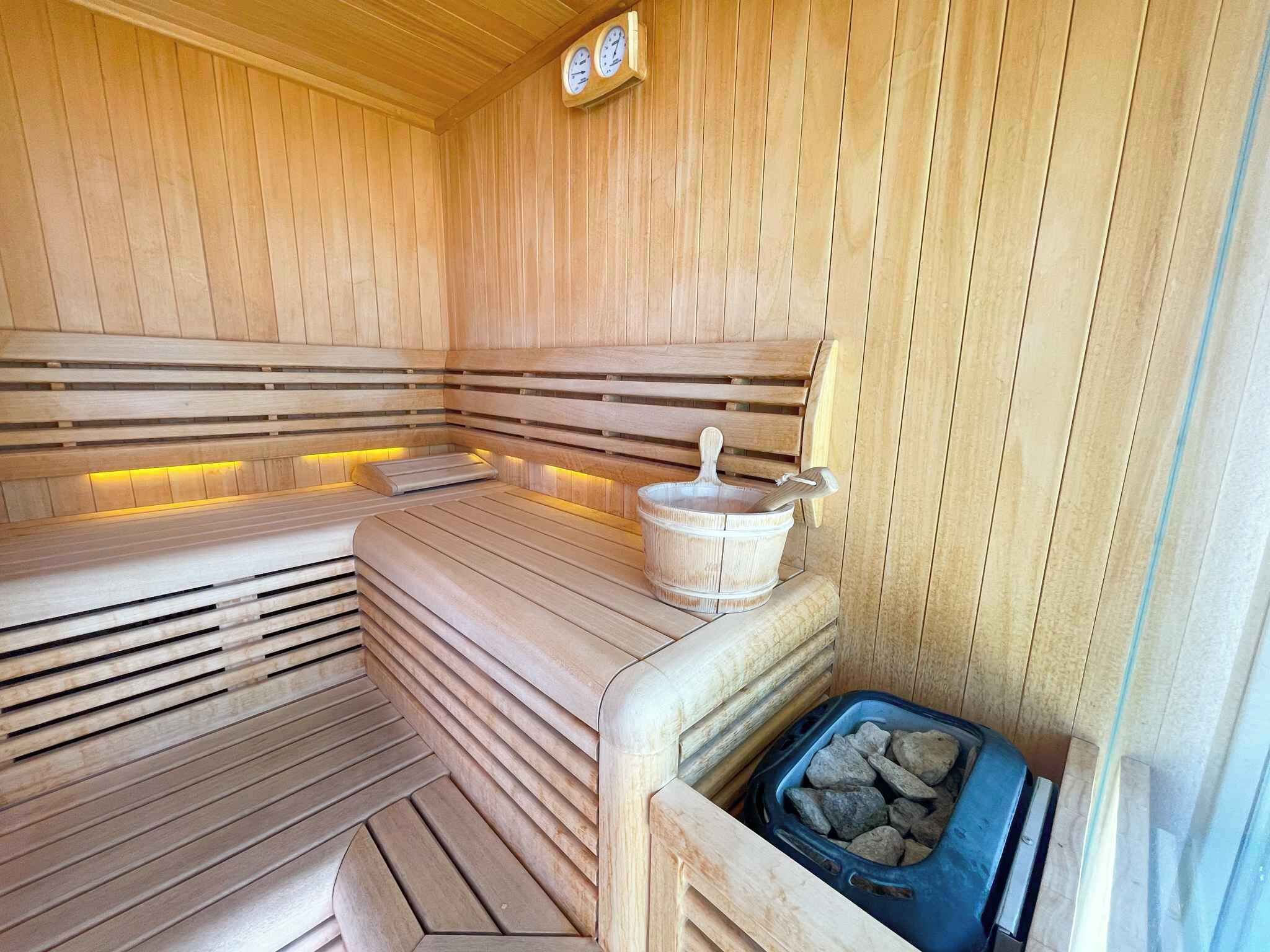 Una sauna con bancos de madera, un balde y un recipiente lleno de piedras.
