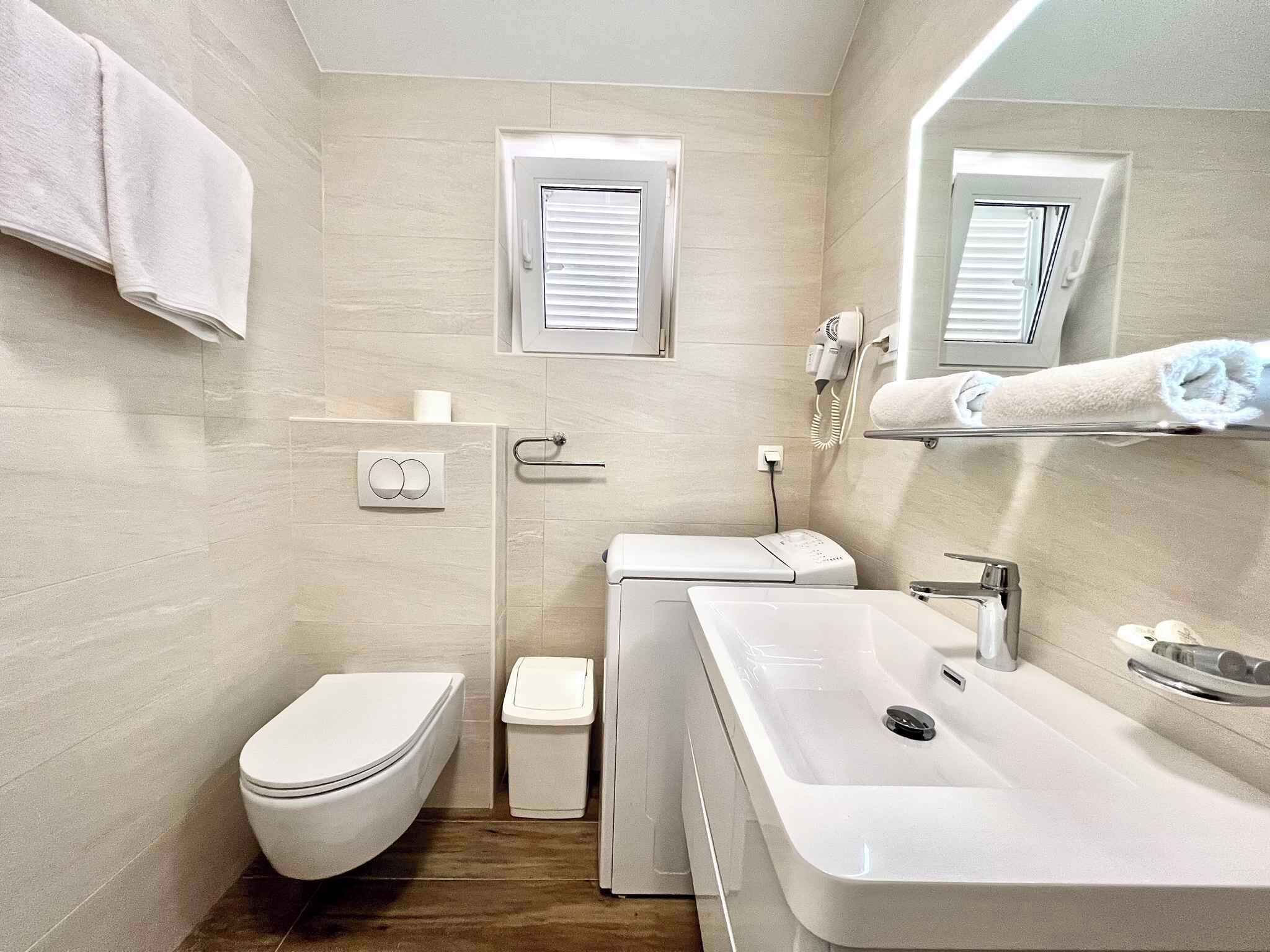Een moderne badkamer met toilet, bidet, wastafel en handdoekhouder.