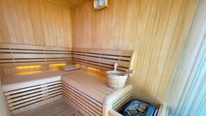 A sauna with wooden slats, a stone basin, and a blue container with rocks. - Studio with air conditioning, whirlpool and large terrace with sea view (Dramalj)