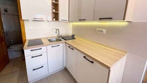 A modern kitchen with white cabinets, a wooden countertop, and a built-in sink. - Studio with air conditioning, whirlpool and large terrace with sea view (Dramalj)