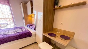 A compact bedroom with a bed, a small table with two chairs, and a wooden shelf above the table. - Studio with air conditioning, whirlpool and large terrace with sea view (Dramalj)