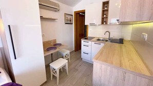 A compact kitchen with white cabinets, a wooden countertop, and a small dining area with a bench. - Studio with air conditioning, whirlpool and large terrace with sea view (Dramalj)