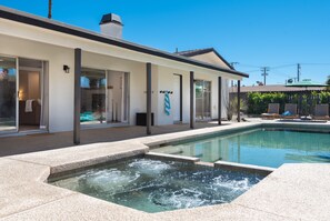 Ein modernes Gebäude mit Swimmingpool, großen Fenstern und einer überdachten Außenbereich mit Liegestühlen.