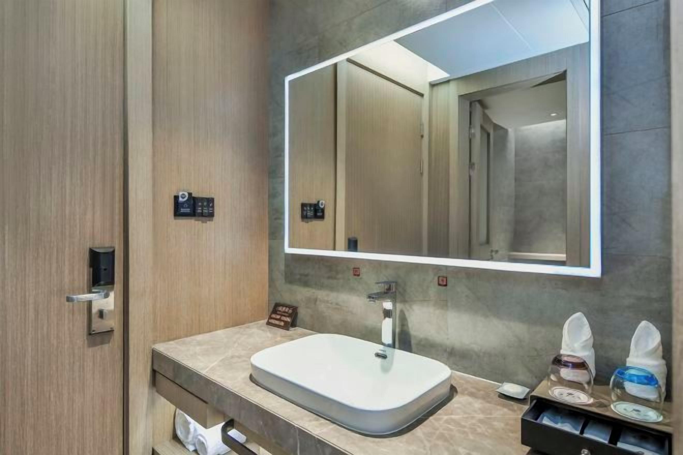 Un baño moderno con un espejo grande, un lavabo y un dispensador de toallas.