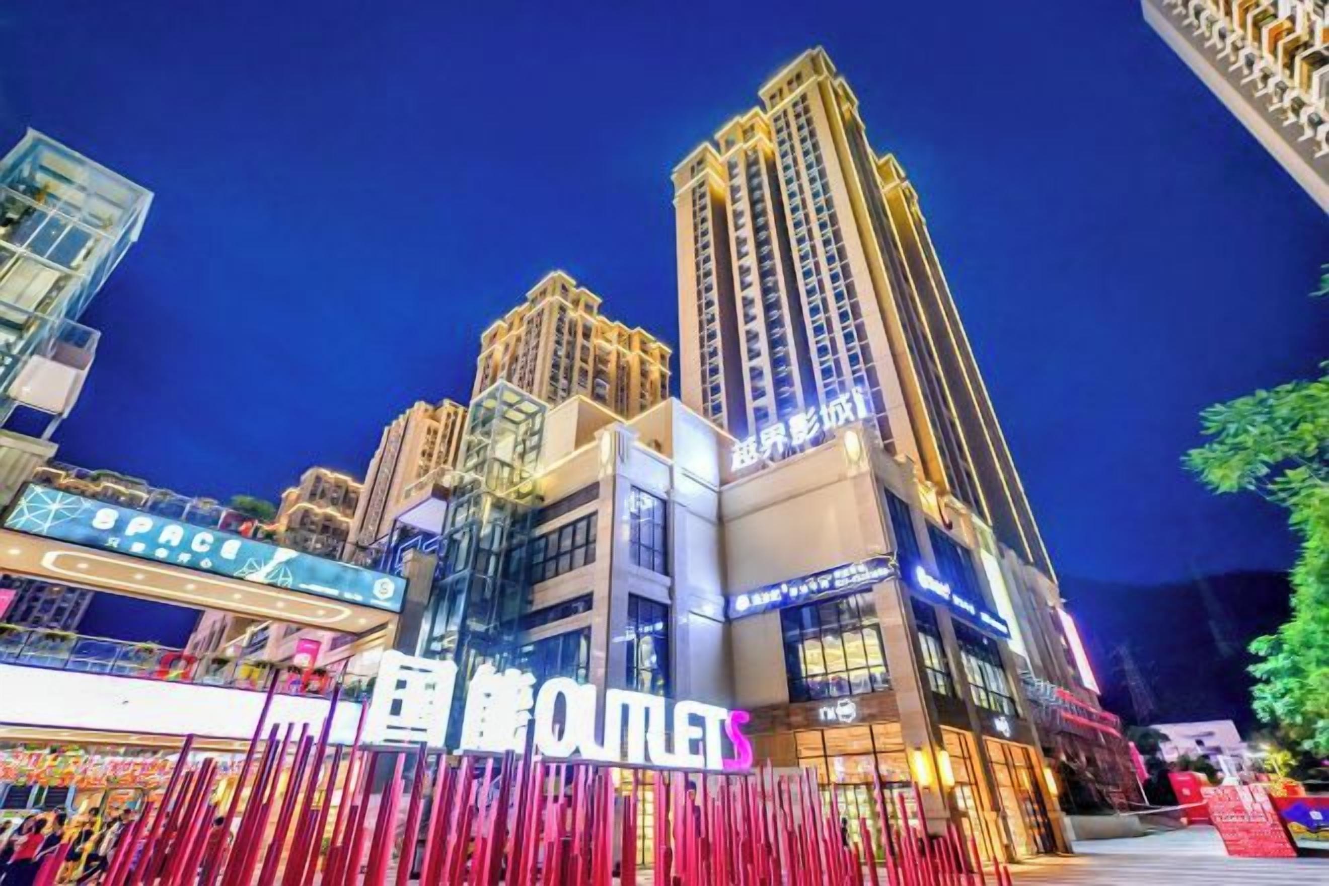 A high-rise building with illuminated signage, a prominent 'OUTLETS' sign, and a modern architectural design.