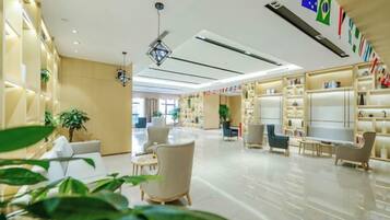 A hotel lobby with seating areas, a reception desk, and a large window.